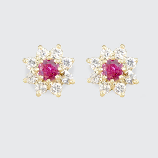 Pair of gold earrings with pink/red rubiy gemstones on a light gray background