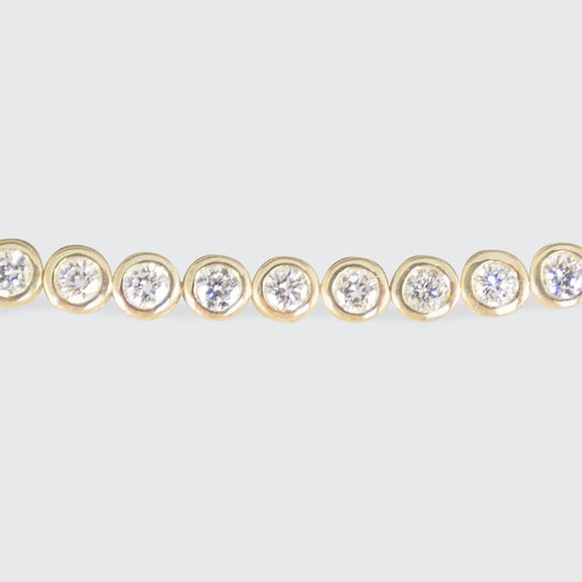 Gold bracelet with diamond gemstones on a light gray background