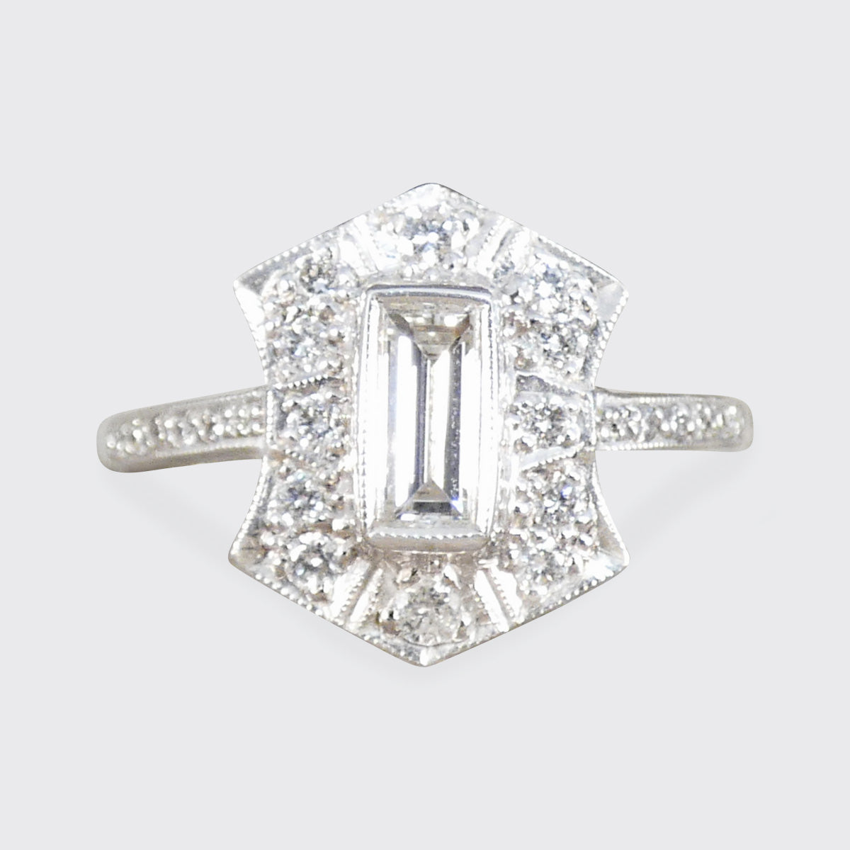 Diamond ring with a rectangular center stone on a light gray background