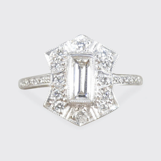 Diamond ring with a rectangular center stone on a light gray background