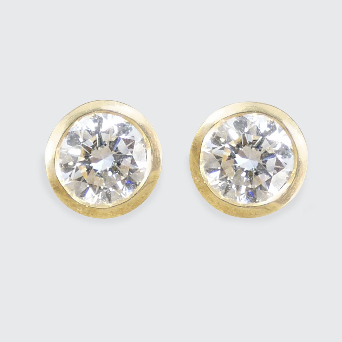 Pair of gold earrings with Diamond gemstones on a light gray background