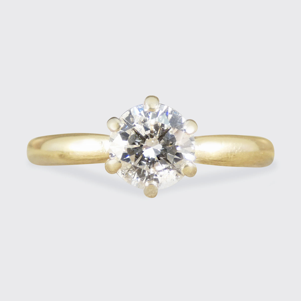 Gold ring with a diamond on a light gray background