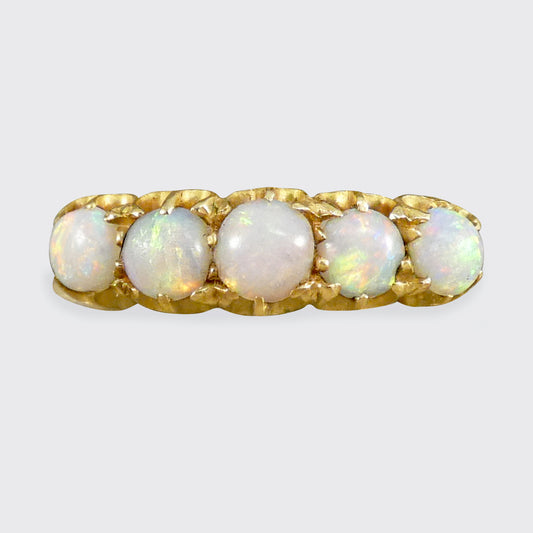 Gold ring with five opal stones on a white background
