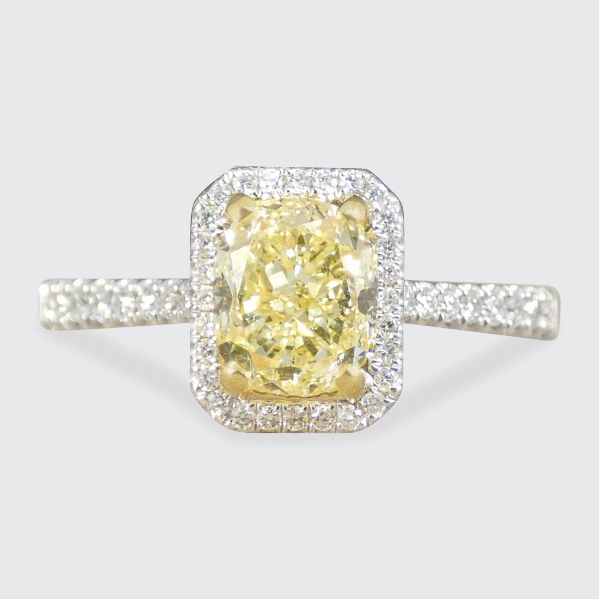Diamond ring with a yellow gemstone on a light gray background