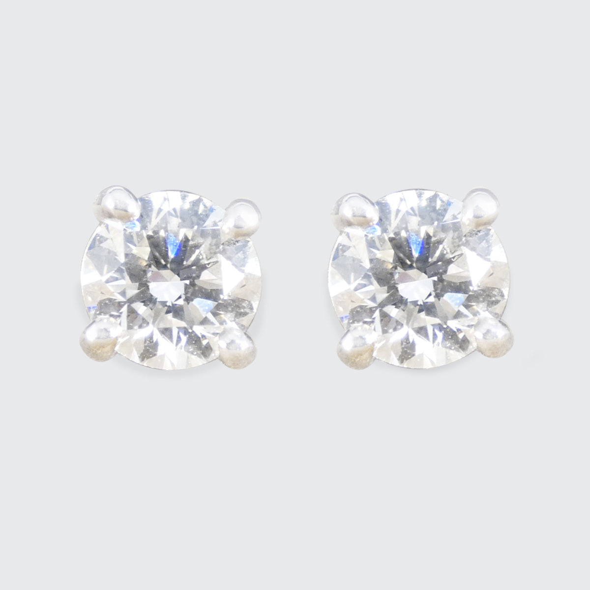 Pair of diamond stud earrings on a light grey background.