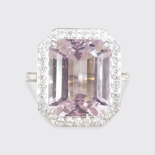 Pink gemstone ring with diamond halo on a light gray background