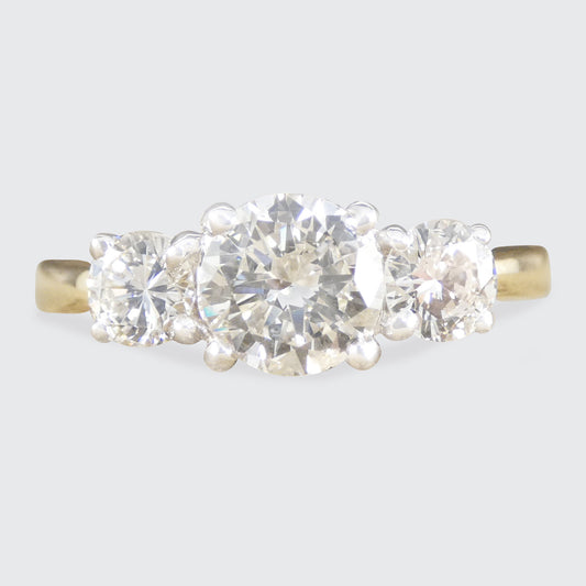 Gold ring with three diamonds on a light gray background