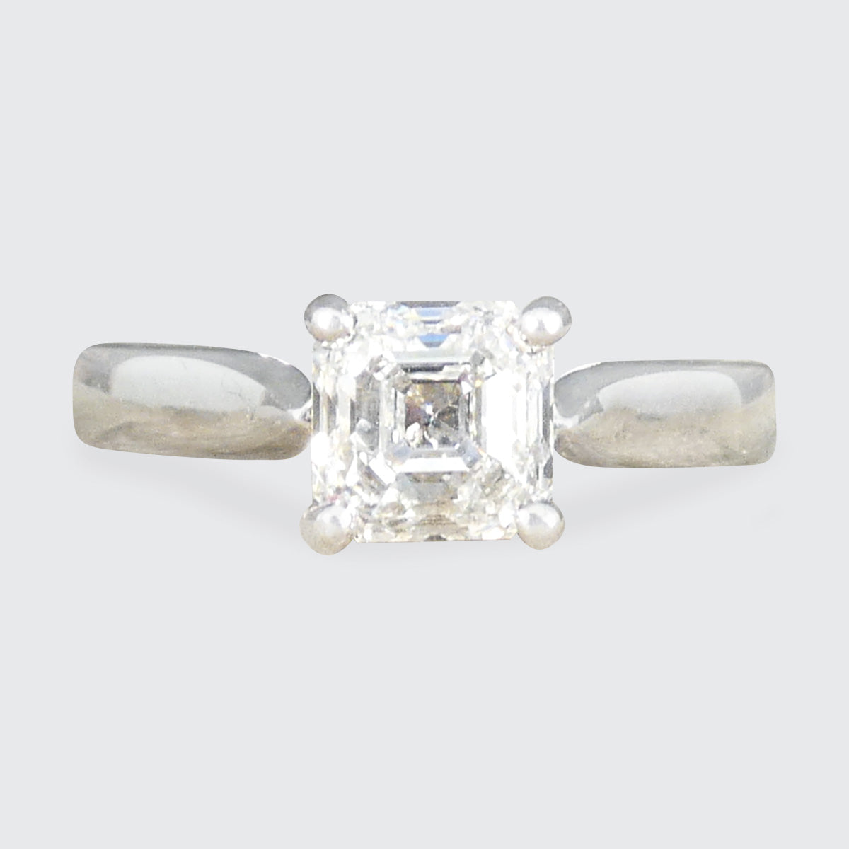 A Squared Emerald Cut Diamond Solitaire Engagement Ring in a four claw setting with a chunky Platinum band and modern feel.