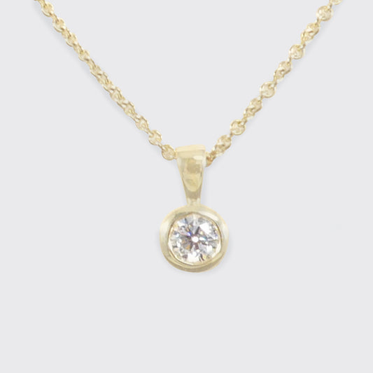 Gold necklace with a diamond pendant on a light gray background