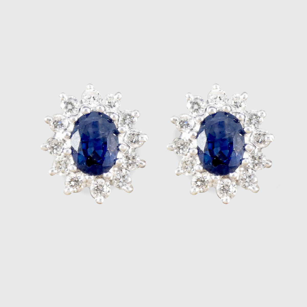 Pair of sapphire earrings with diamond accents on a light gray background
