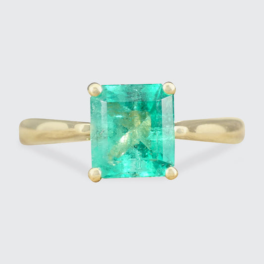 Gold ring with a green gemstone on a light gray background
