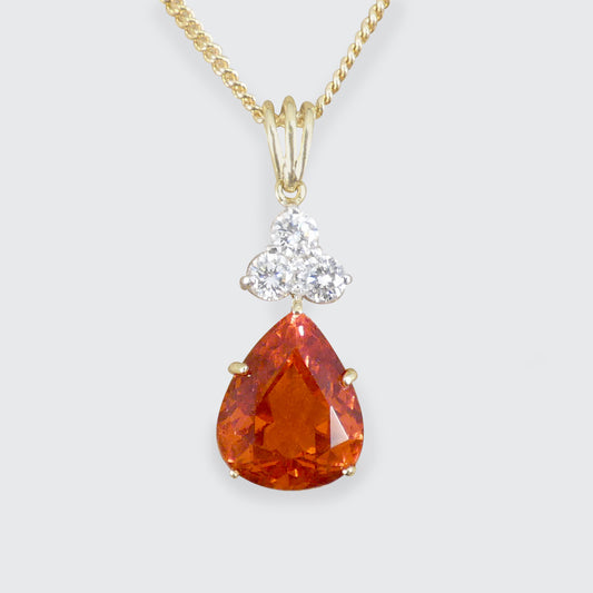 Gold necklace with a teardrop-shaped orange gemstone and smaller diamond pendant on a white background