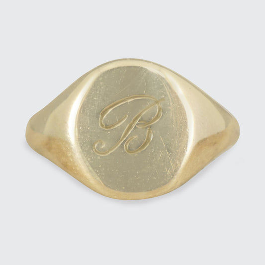 A classic signet ring with a B engraved on the face in yellow gold.