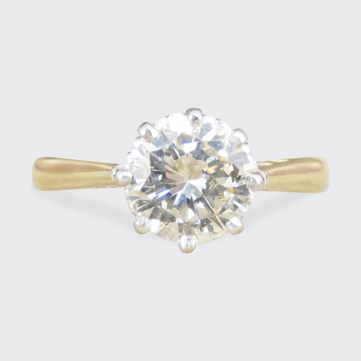 Gold ring with a large diamond on a light gray background