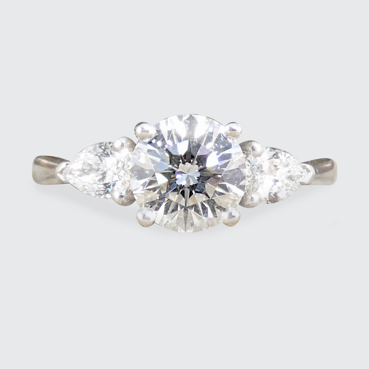Diamond ring with a three gemstones on a light gray background