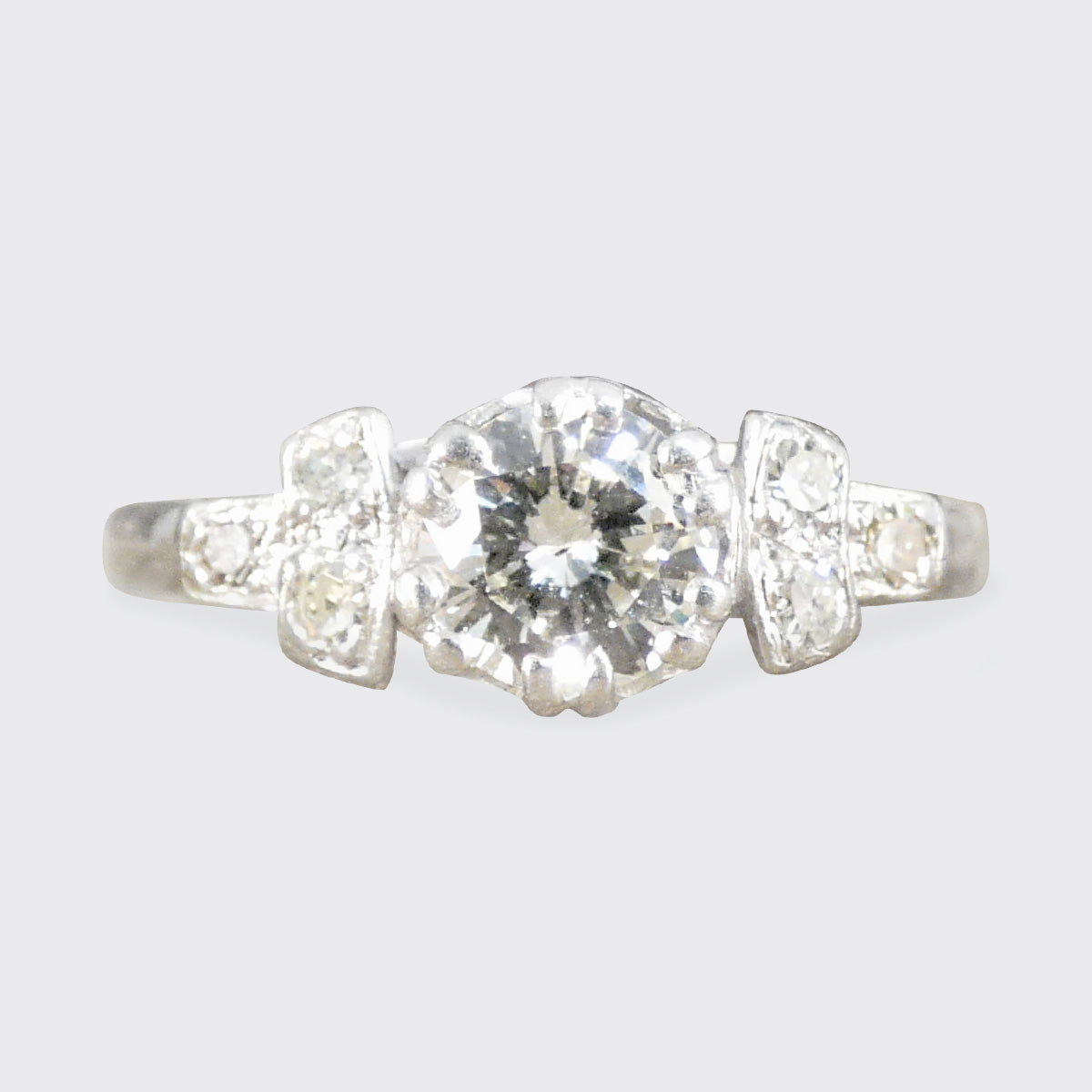 Platinum ring with a central diamond flanked by two smaller diamonds on a light gray background