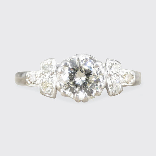 Platinum ring with a central diamond flanked by two smaller diamonds on a light gray background