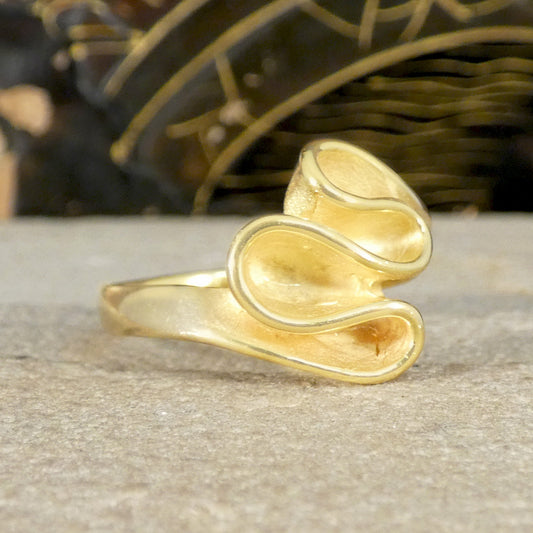 Gold ribbon style ring with a textured design on a neutral background