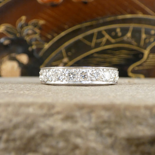 A full diamond eternity ring in 18ct white gold. Displayed on an ornate background