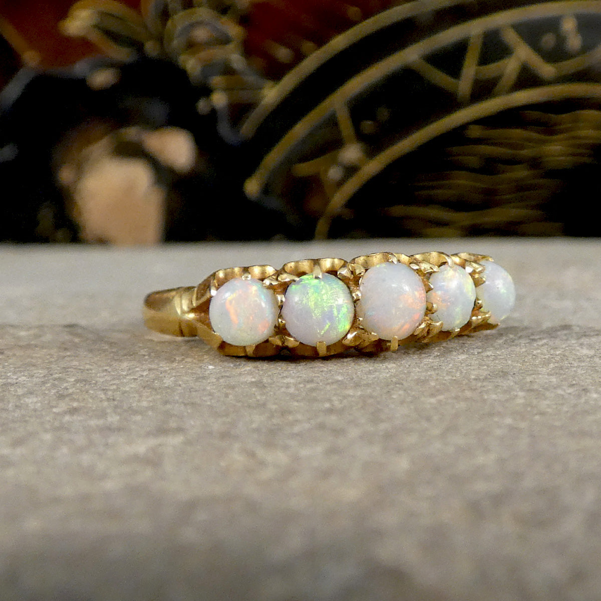 Gold ring with opal stones on a stone surface
