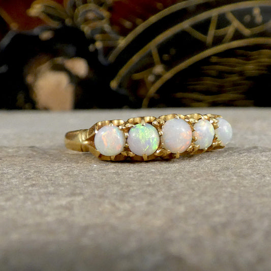 Gold ring with opal stones on a stone surface