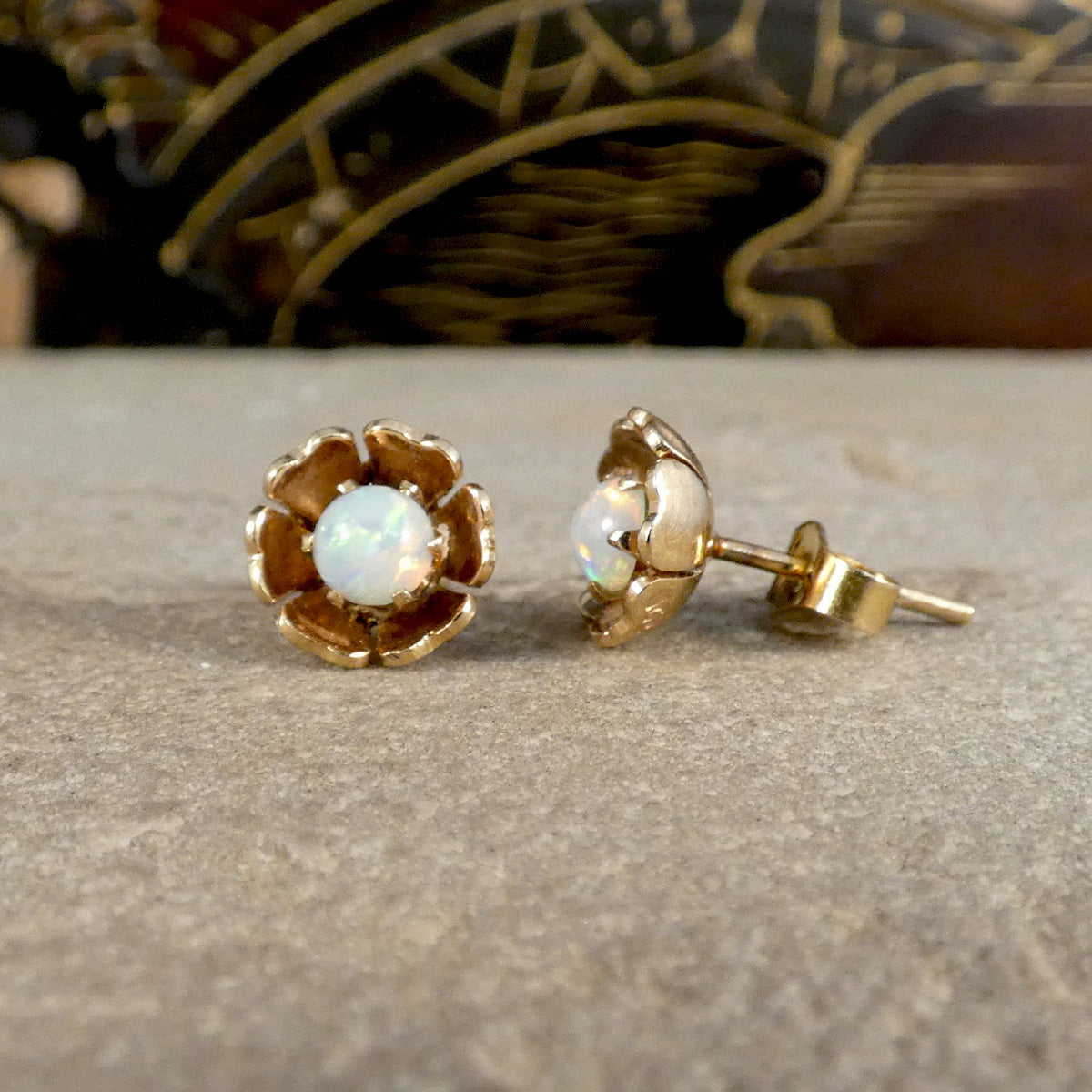 Gold earrings with opal stones on a textured surface