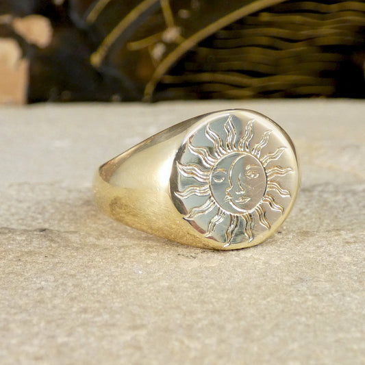 A solid yellow gold signet ring with a face engraved with a sun and moon