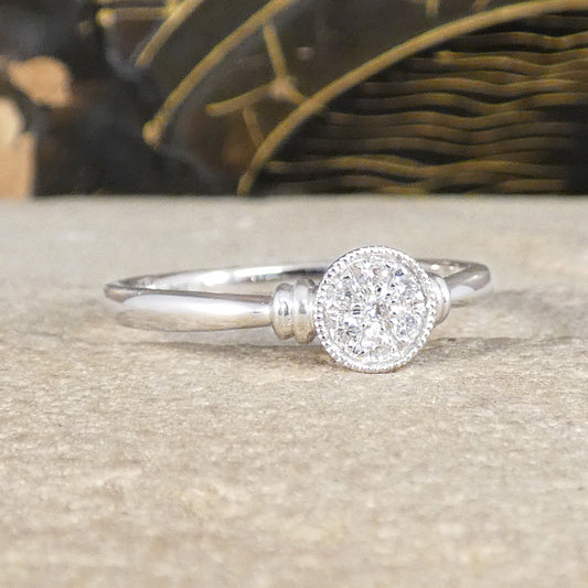 A diamond set disc shaped cluster ring with a double donut shoulders in Platinum.