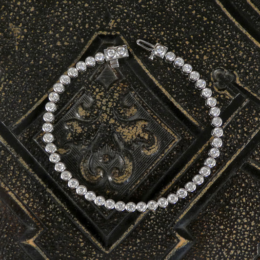 A diamond tennis bracelet in a bezel setting in Platinum showing open snap lock