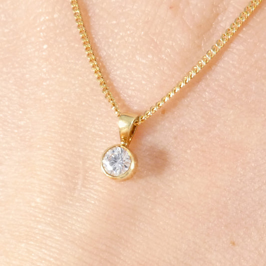 Elegant 18ct yellow gold solitaire pendant necklace shown worn, featuring a round brilliant-cut diamond in a secure bezel setting on a delicate but sturdy chain.