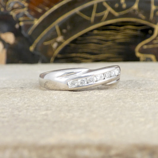 Silver ring with small diamonds on a textured surface with a decorative background