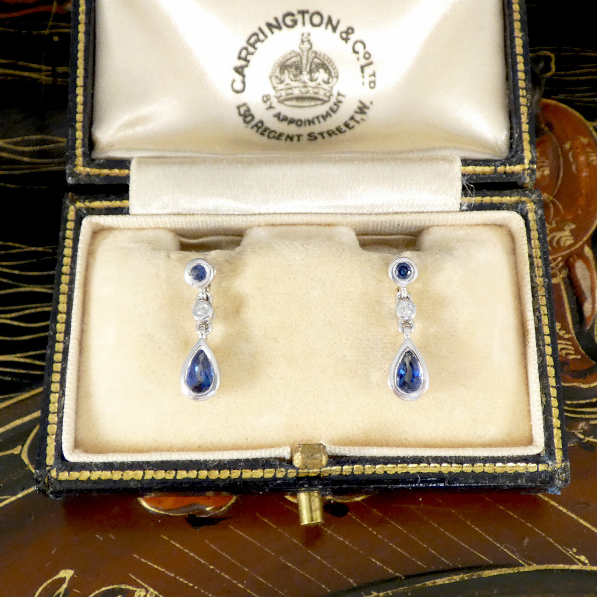 Teardrop-shaped sapphire and diamond earrings in a jewellery box.