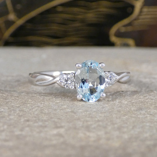 Modern Oval Cut Aquamarine and Brilliant Cut Diamond Three Stone in Platinum with a slight twist design in the shoulder.
