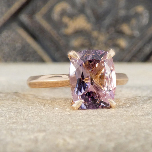 Ring with amethyst gemstone on a textured surface with a blurred decorative background
