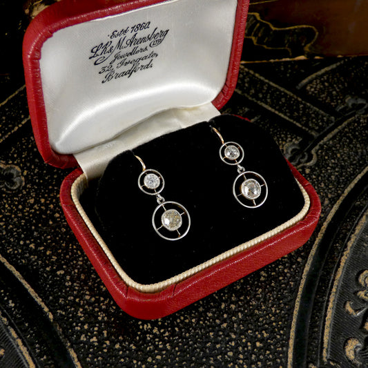Diamond earrings in a red and white jewelry box on an ornate surface