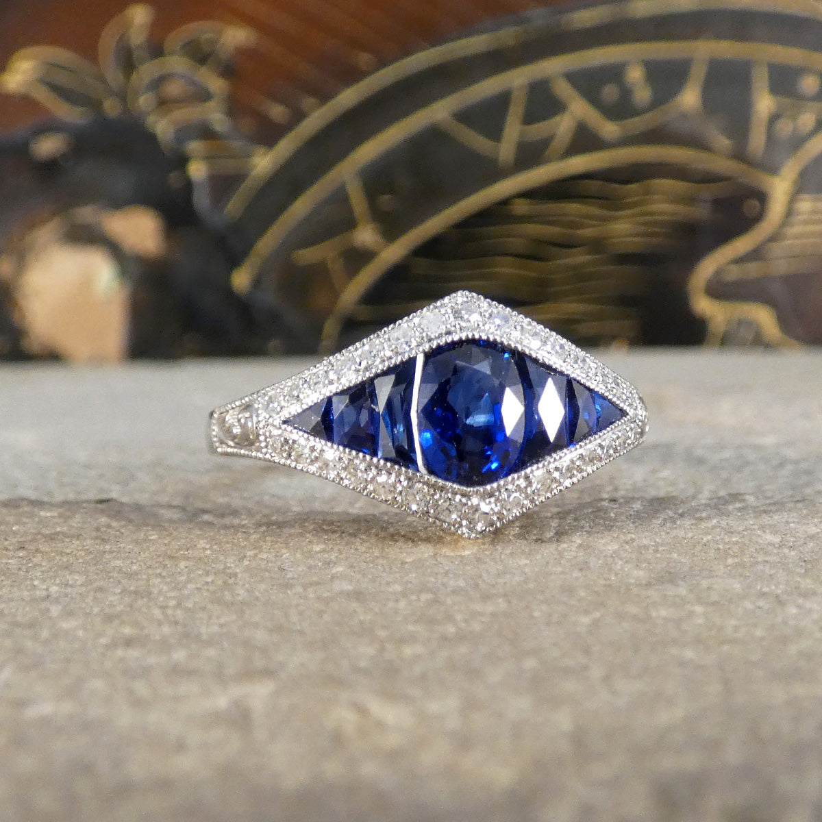 A gorgeous Art Deco style Sapphire and Diamond cluster ring in Platinum. The perfect ring for a unique gift.