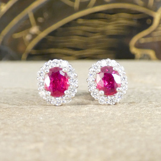 Pair of earrings with red gemstones and silver surrounds on a neutral background