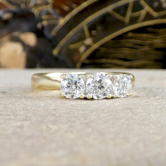Gold ring with three diamonds on a textured surface
