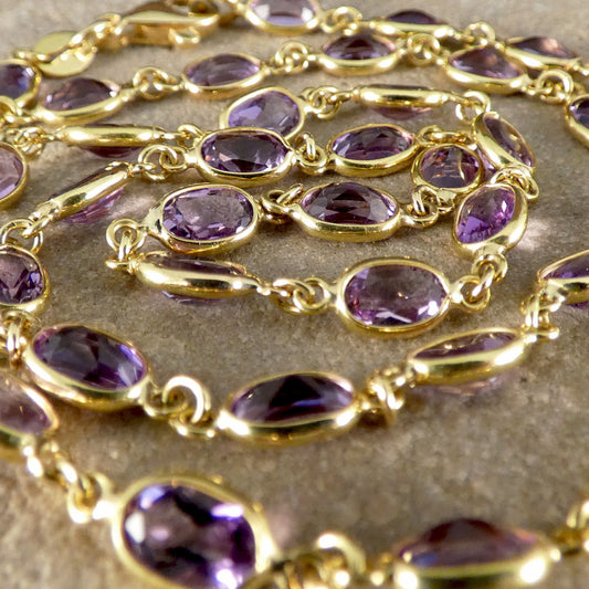Gold chain with purple gemstones on a textured surface