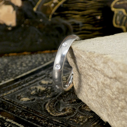 Platinum ring with small stones on a textured surface