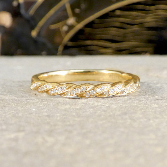 Gold ring with diamond accents on a textured surface