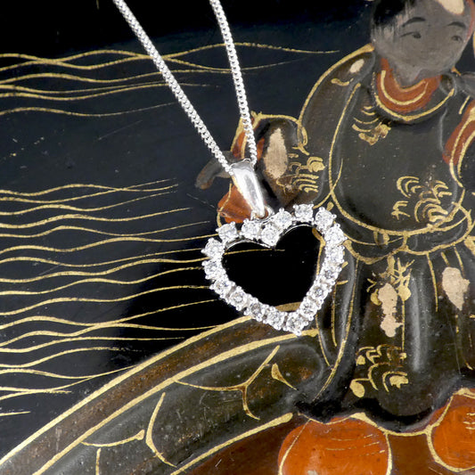 Heart-shaped diamond pendant on a chain against an ornate background
