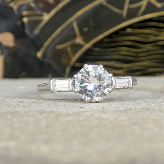 Art Deco-inspired platinum ring featuring a 0.90-carat early brilliant-cut centre diamond, flanked by two 0.10-carat baguette-cut diamonds on either side. The timeless design emphasises geometric elegance and vintage charm.
