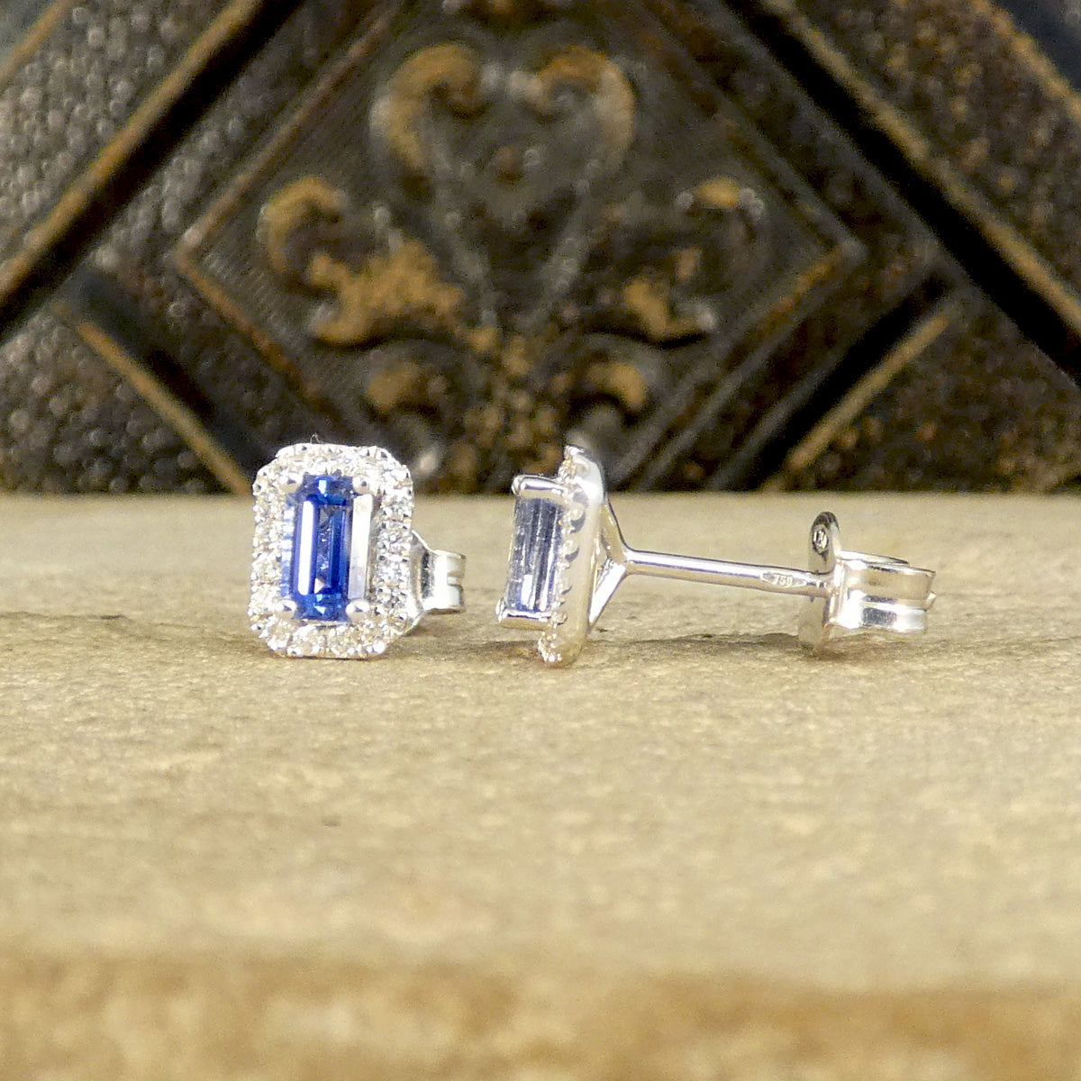 A pair of Sapphire and Diamond Halo Cluster Stud Earrings in 18ct White Gold. One shown from the front and the other from the side showing the martini setting and butterfly back.
