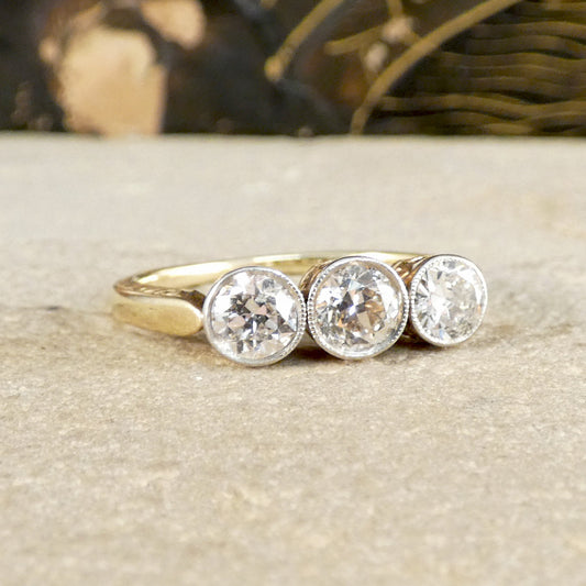 Gold ring with three diamonds on a textured surface