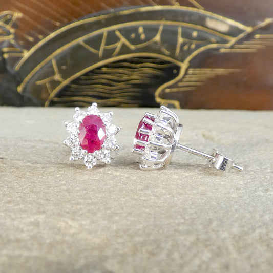 Ruby and Diamond Cluster Stud Earrings in 18ct White Gold, in a classic setting that will stand the test of time. Featuring a bright and pinkish oval cut Ruby in each stud with a cluster of Diamonds in 18ct White Gold. Shown from the front and the side to see butterfly back.