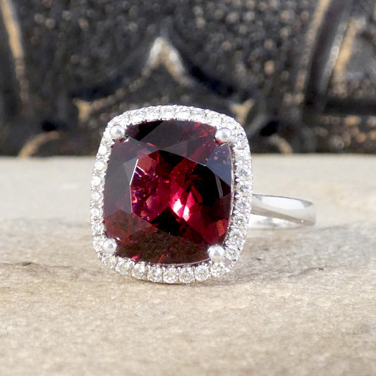 A gorgeous bright and beautiful 4.28ct cushion cut garnet in a four claw setting surrounded by a halo of brilliant cut diamonds. A lovely ring and perfect gift for anyone who likes a burst of colour.