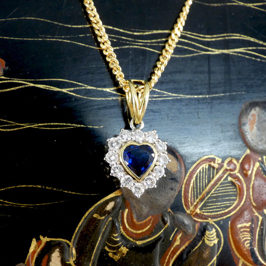 Heart shaped Sapphire and Diamond cluster pendant necklace in 18ct Yellow Gold. Showing a lovely deep blue hue. with a rub over bezel setting.
