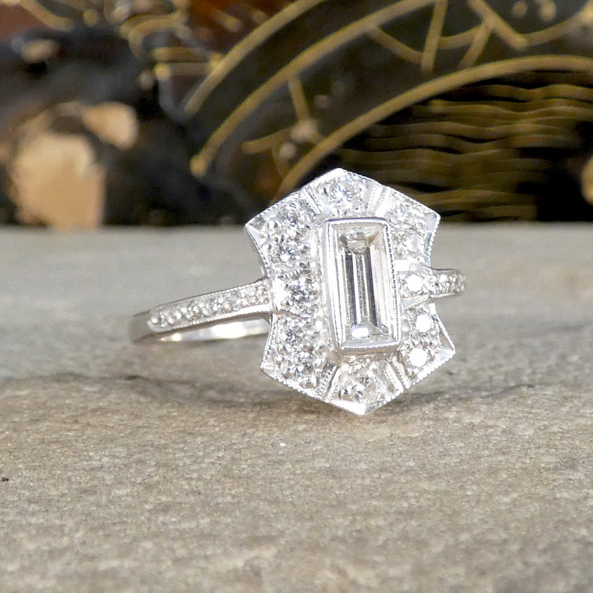Diamond ring with a rectangular center stone on a textured surface