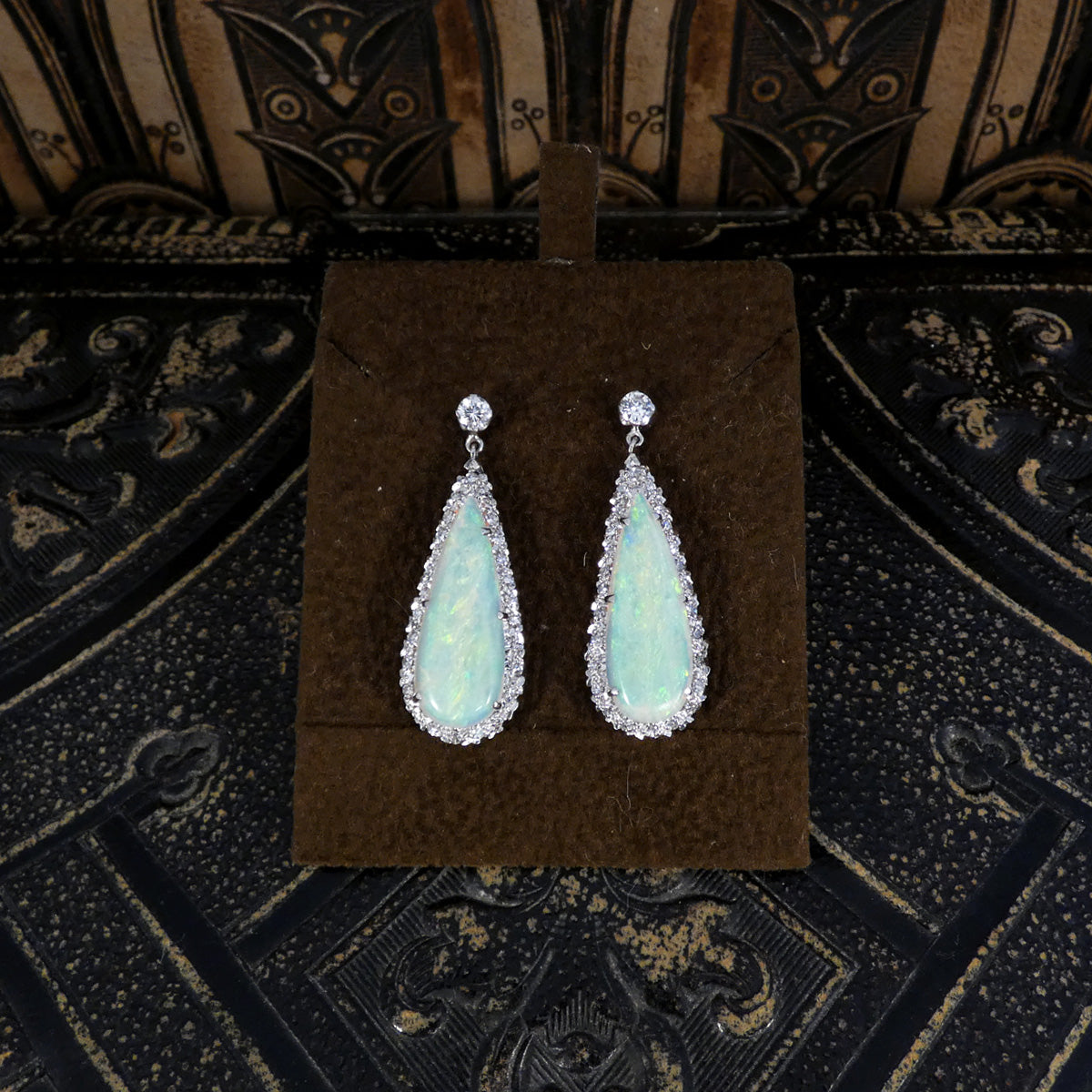 Elegant vintage opal and diamond cluster drop earrings in platinum, featuring pear-shaped opals surrounded by halos of brilliant diamonds and secured with round diamond studs.